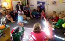 students seated on floor watching teacher